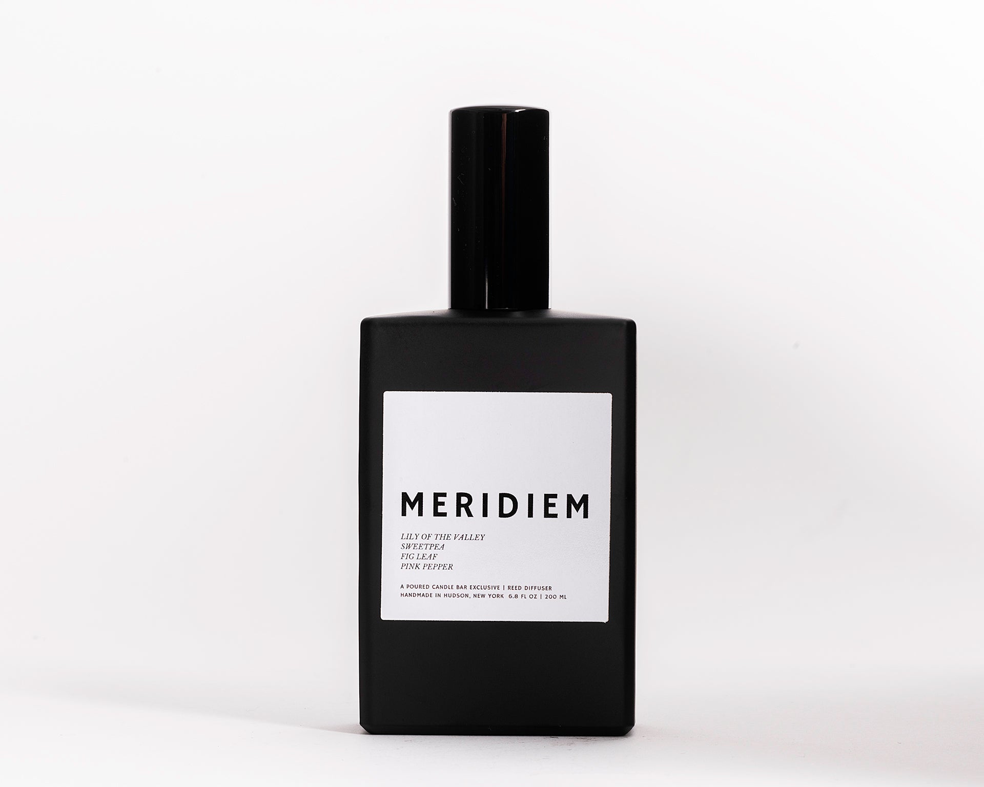 100 ml room spray in a black rectangular glass vessel. Profile Description: Green grass with sweet fruit + soft spice  Notes: Aldehydes, Lilly of the Valley, Grass, Sweet Pea, Fig Leaf, Pink Peppercorn
